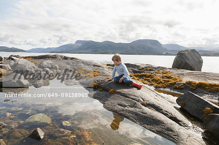 Boy looking at fjord rockpool, Aure, More og Romsdal, Norway