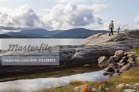 Man and son walking on fjord rock formation, Aure, More og Romsdal, Norway