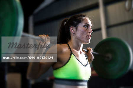 Woman exercising in gym, using barbell