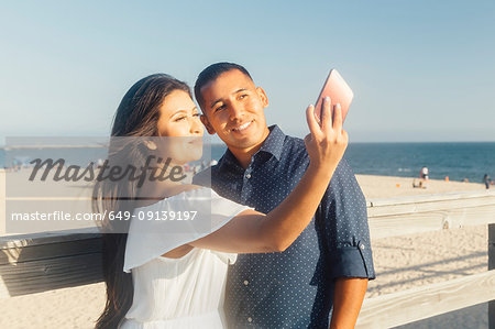 Couple beside beach, talking selfie, using smartphone, Seal Beach, California, USA