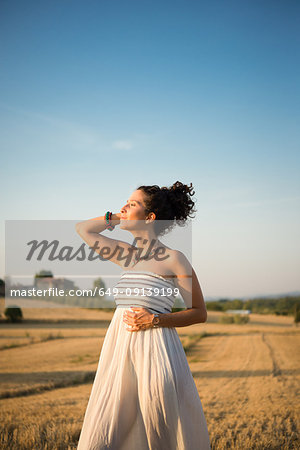 Mid adult woman, standing in field, enjoying sunshine