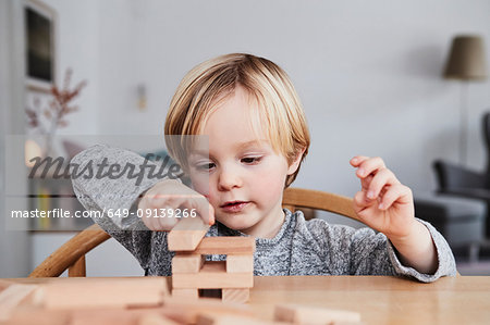Portrait of young boy, building structure with wooden building blocks