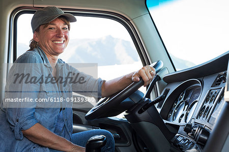 Caucasian woman truck driver in the cab of her commercial truck at a truck stop