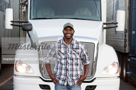 Black man truck driver near his truck parked in a parking lot at a truck stop