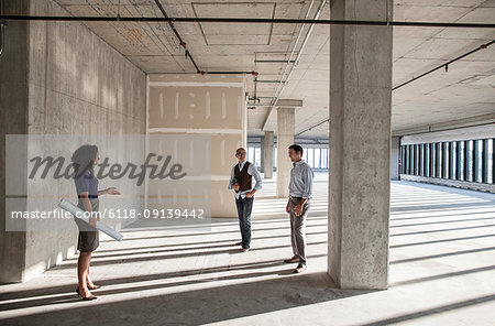 Mixed race team of business people touring a new empty raw office space.