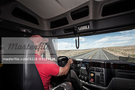 Interior cab view of a Caucasian man driving his  commercial truck.