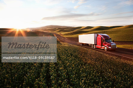 Peterbilt Class8 commercial truck driving through farmlands in eastern Washington, USA at sunset.