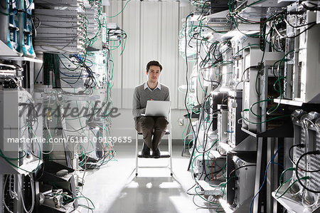 Caucasian male technician working on computer servers in a computer server farm.