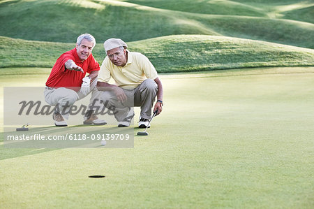Senior golfers judging the lie on one of the greens of the golf course.