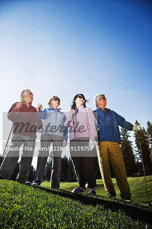 Two young senior golfing couples on the course and ready to play.