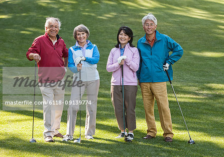 Two young senior golfing couples on the course and ready to play.