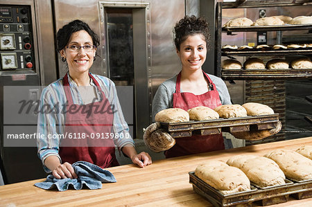 Female bakers working at a bakery with loaves of bread.