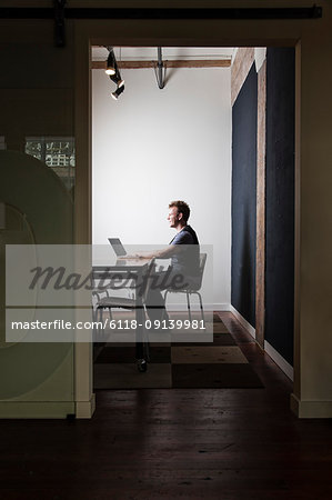 Caucasian male worker using a laptop computer at a conference room table