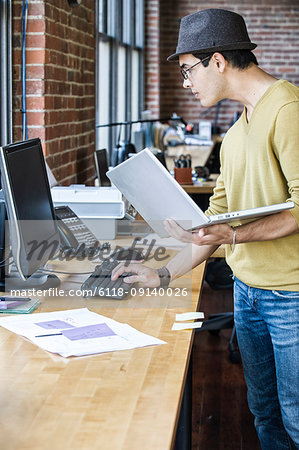 Hispanic male at his office workstation in a creative office.