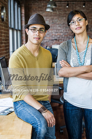 Asian woman and Hispanic man together at a creative office work station.