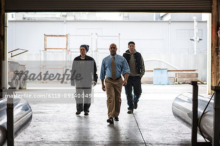 Workers and management person walking through a door into a sheet metal factory.