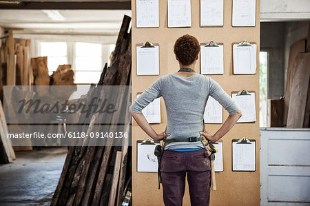 Woman factory worker checking project inventory in a woodworking factory.