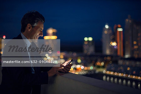 Businessman on high rise rooftop using mobile phone