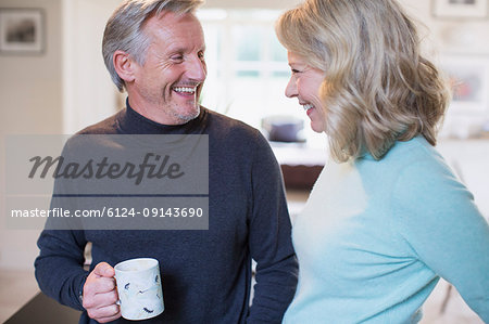 Smiling mature couple talking and drinking coffee