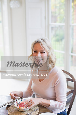 Portrait smiling mature woman eating grapefruit