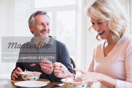 Smiling mature couple eating breakfast