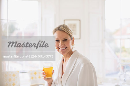 Portrait smiling, confident mature woman in bathrobe drinking juice