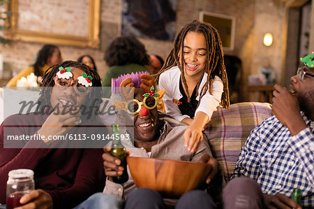 Playful multi-generation family wearing Christmas glasses, enjoying popcorn