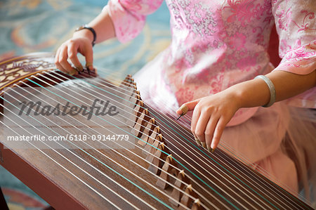 High angle close up of woman playing traditional Japanese Koto string instrument.
