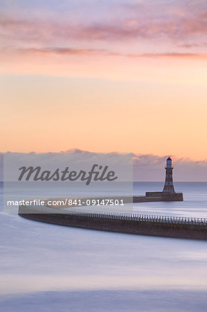 The colours of a winter sunrise over the curving pier and lighthouse at Roker, Sunderland, on the North East Coast, England, United Kingdom, Europe
