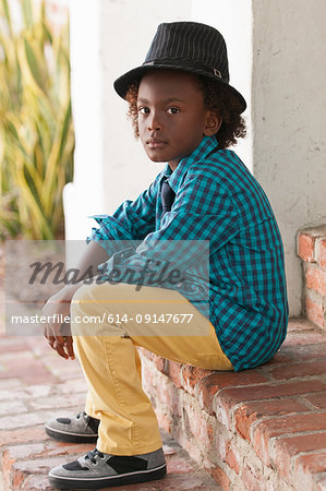 Portrait of young boy, sitting outdoors, wearing fedora