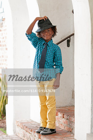 Portrait of young boy, standing outdoors, wearing fedora