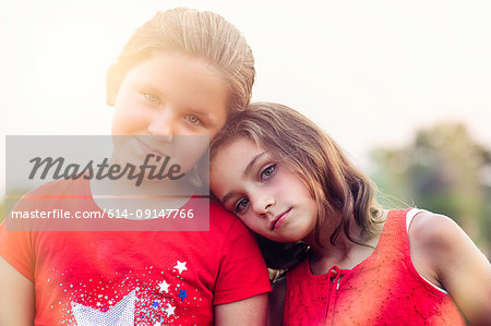 Portrait of girl with head on friends shoulder looking at camera