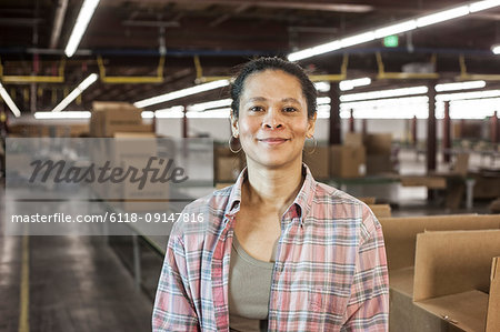 Portrait of an African American female warehouse worker in a large distribution warehouse with products stored in cardboard boxes.