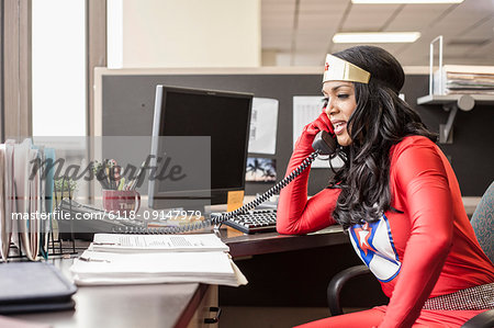 A black office superhero businesswoman takes a call in her office from a client.