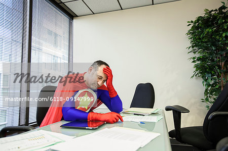 A middle aged Caucasian office super hero ponders the stress of the job.