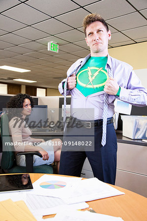 A Caucasian man office super hero gets ready for action in his office.