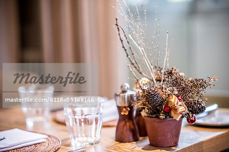 Close up of drinking glasses and Christmas decorations on wooden dining table.