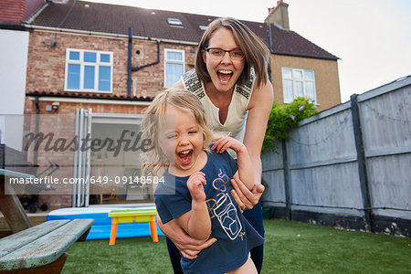 Mother and toddler daughter playing in garden, portrait