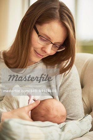 Woman breast feeding baby daughter on sofa