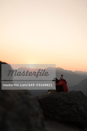 Woman with dog on hilltop at sunrise, Rattlesnake Ledge, Washington, USA