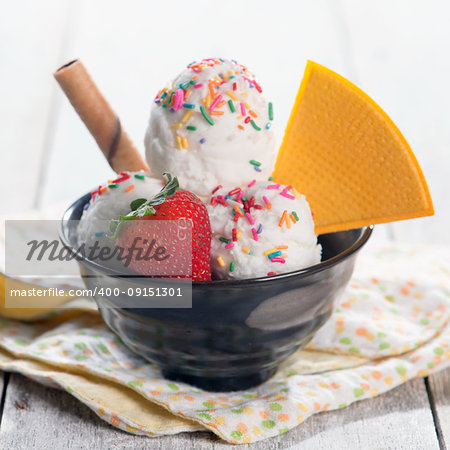 Milk ice cream in bowl with waffle on white rustic wooden background.