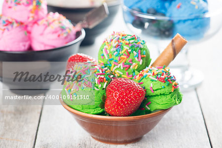 Green ice cream in bowl on wooden background.