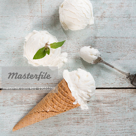 Top view vanilla ice cream wafer cone on white rustic wooden background.
