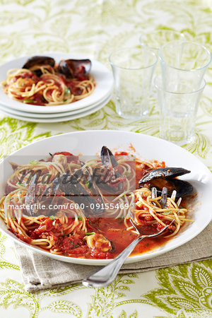 Spaghetti Marinara with mussles in a white bowl on a green, patterned linen tablecloth