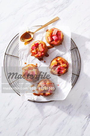 Rhubarb mini cakes with caramel sauce on a cooling rack on white marble