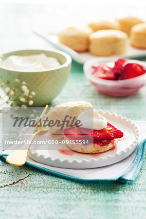 Scones with strawberries and whipped cream on a fancy white plate