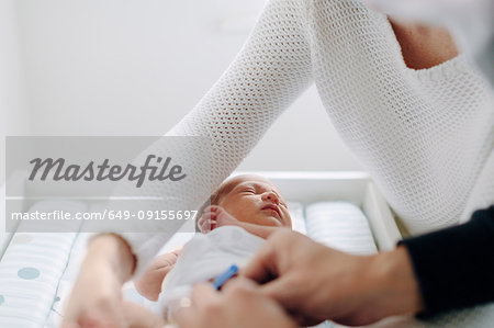 Mother and father dressing newborn baby