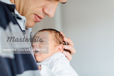 Father holding newborn baby girl to his chest, mid section, close-up