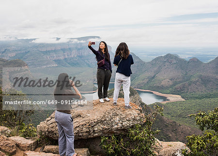 Three young female tourists looking out and taking selfie from The Three Rondavels, Mpumalanga, South Africa