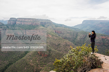 Young female tourist photographing landscape from The Three Rondavels, Mpumalanga, South Africa